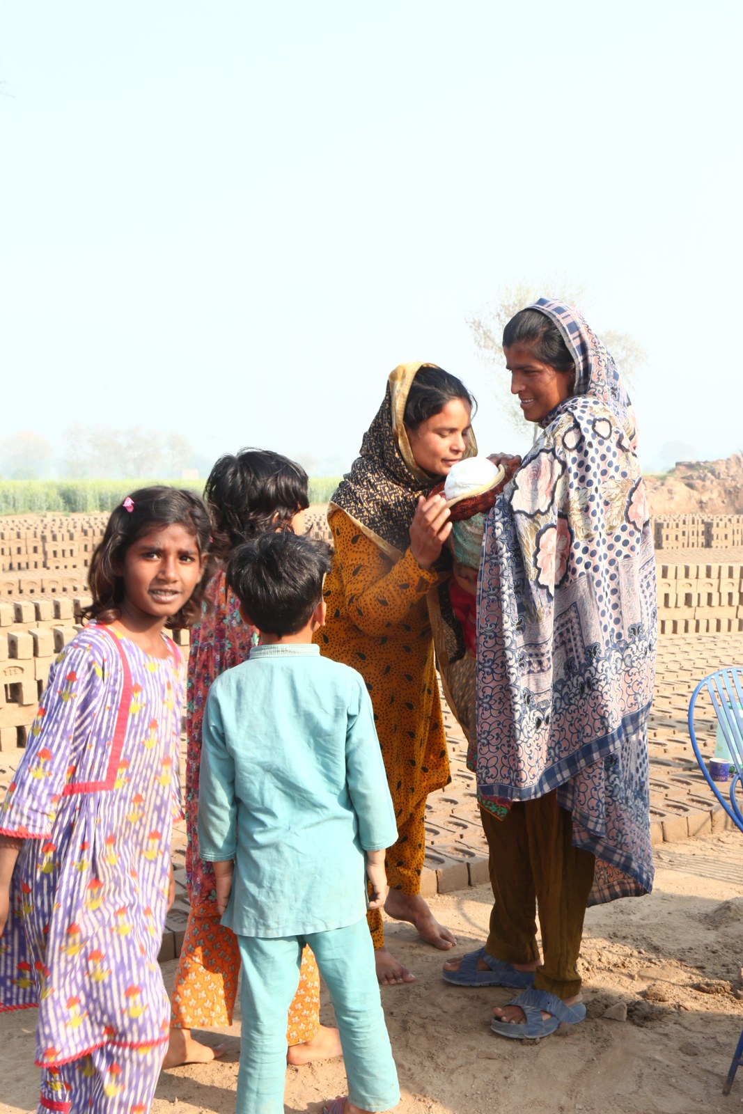 Women and children at the kiln, with a mother holding her baby